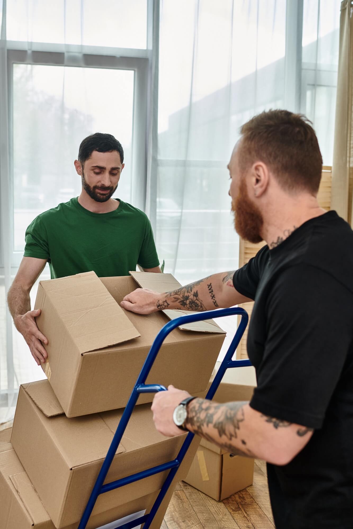 Kaksi miestä lastaa yhdessä laatikoita muuttoautoon muuton aikana.